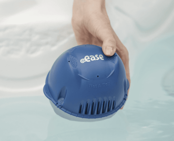 A person is holding a FROG @Ease Floating Sanitizing System for Hot Tubs in the water.